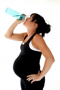Pregnant model drinking water after her physical fitness workout